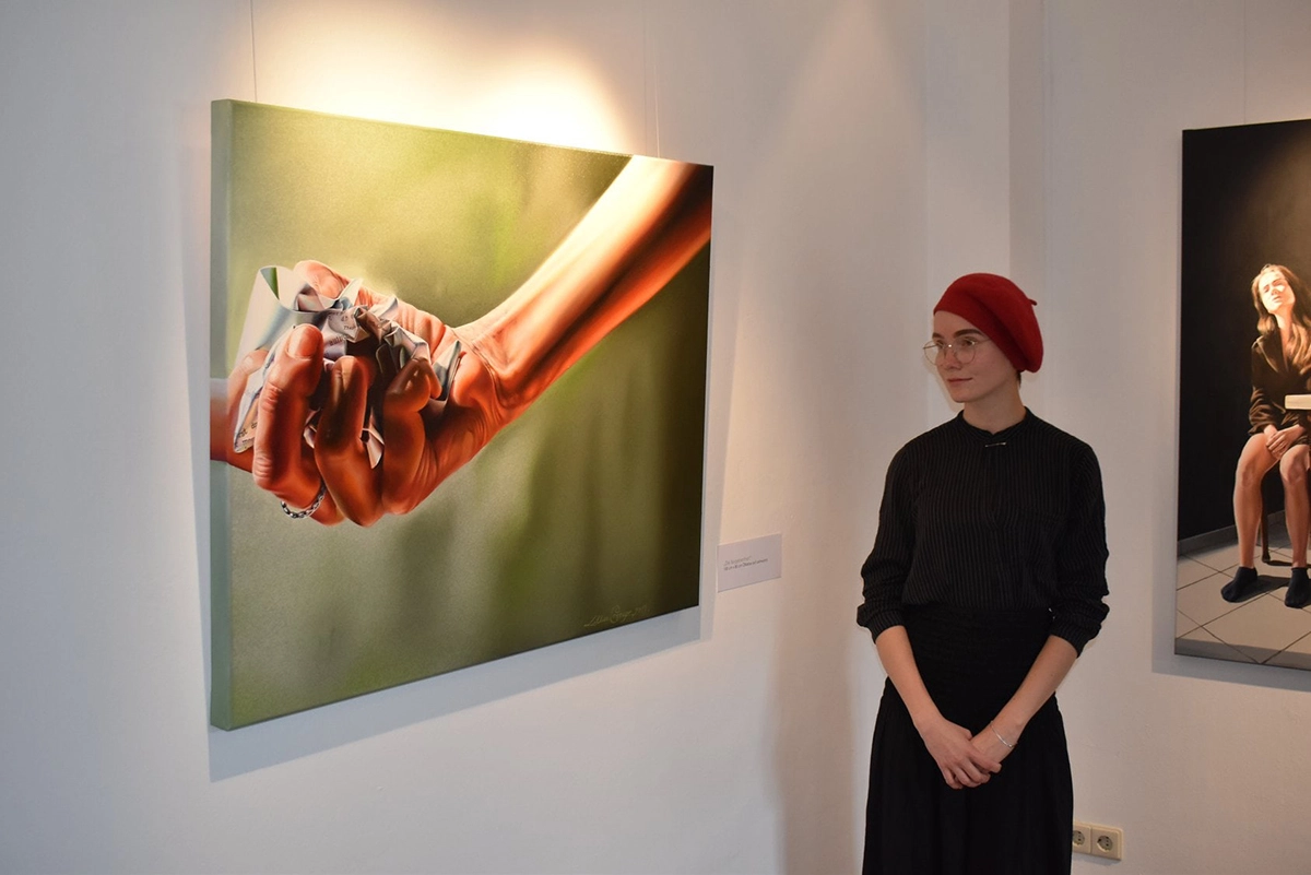 Foto von der Künstlerin neben ihren Werken in einer Ausstellung im Kloster Brunshausen.